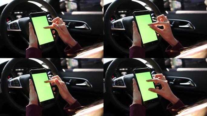 女人在汽车上使用带有绿屏的智能手机
