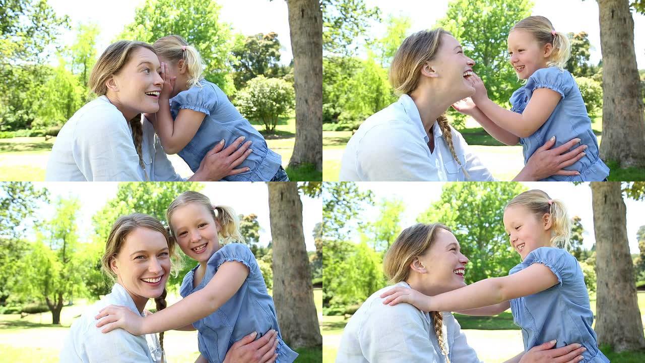 快乐的小女孩在公园里告诉母亲一个秘密