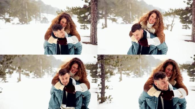 时髦的夫妇在白雪皑皑的森林里享受背负式骑行和接吻