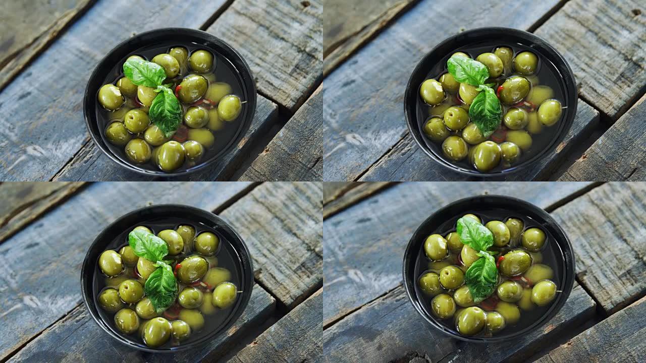 一碗绿橄榄配以香草装饰的醋