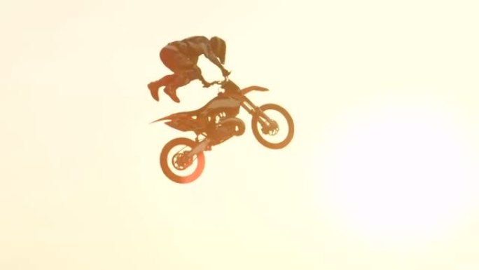 慢动作: 自由式越野摩托车手在日落的阳光下跳跃超人