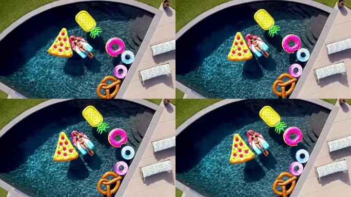 年轻女子躺在现代房子蓝色游泳池的有趣游泳池玩具上
