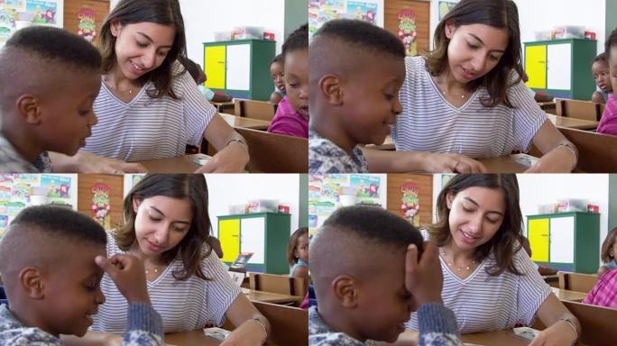 女教师在教室里帮助小学男孩