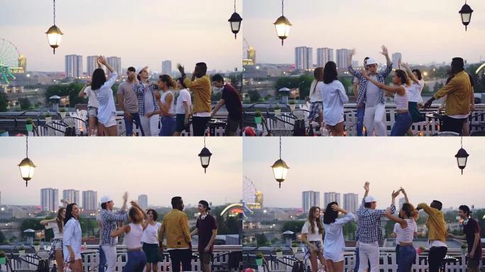 夏天晚上，多种族的朋友在屋顶上跳舞，与DJ一起开酷派对。快乐的青春、娱乐和大城市的概念。