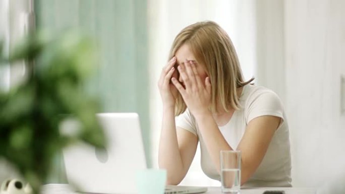 女人在工作中使用笔记本电脑时头痛