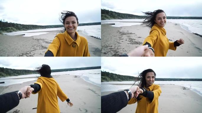 女人牵着男人的手在海滩上微笑。