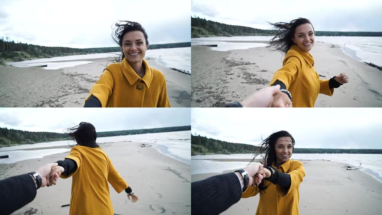 女人牵着男人的手在海滩上微笑。