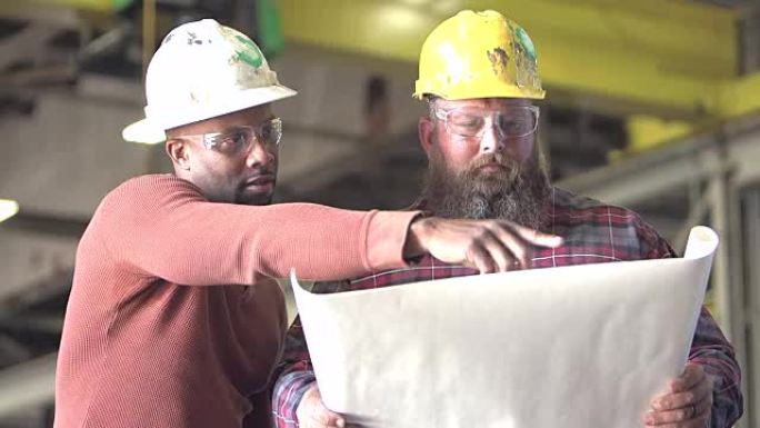 两个工人戴着安全帽，看着计划