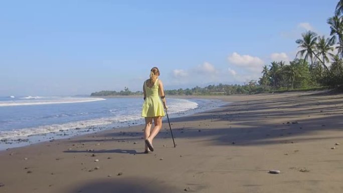 近距离观察拄着拐杖的女孩走在热带岛屿巴厘岛的沙滩上