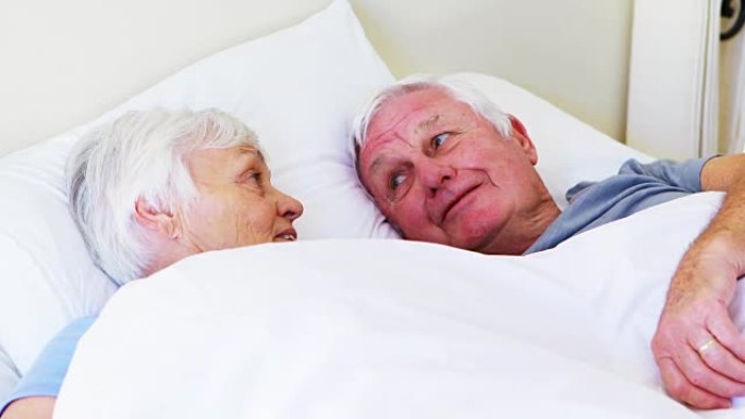 快乐的高级夫妇躺在床上互相交流
