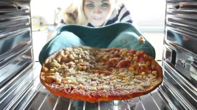 女人将意大利辣香肠比萨饼放入烤箱做饭
