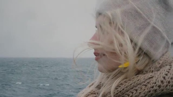 年轻金发女子在阴天乘船旅行的肖像。女人，男人看着大海和海浪