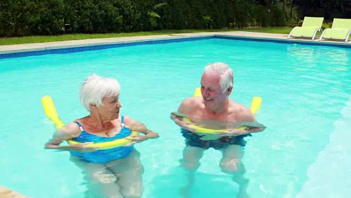 老年夫妇用充气管在游泳池游泳