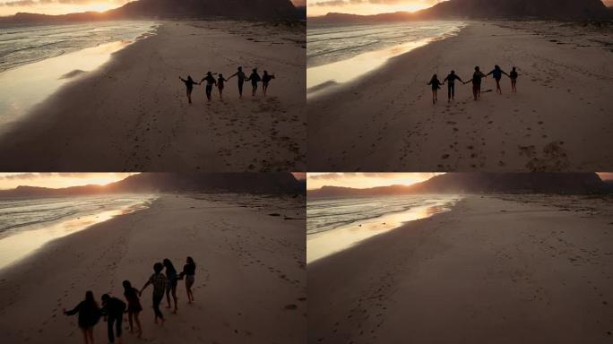 年轻的成年朋友在日落时在海滩散步