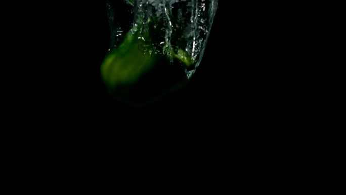 绿色辣椒落在黑色背景下的水中