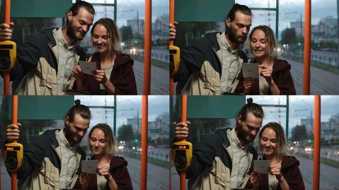 年轻幸福的夫妇在公共交通工具上，在电车上拿着卡。男人和女人晚上在一起玩得开心