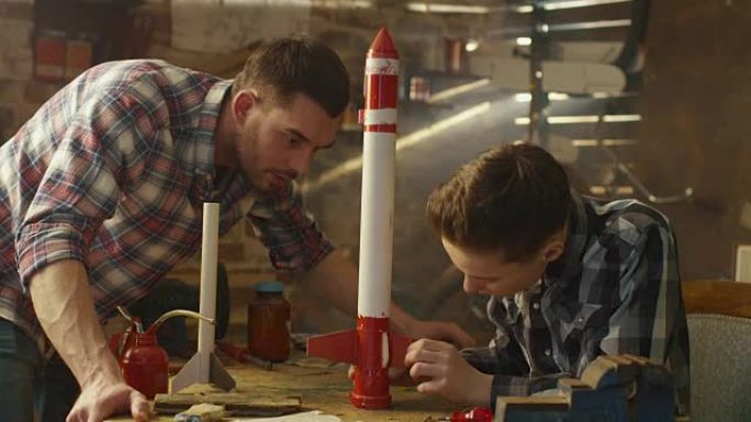 父亲和儿子正在家里的车库里为玩具火箭建模。