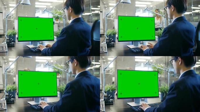 在办公室里，商人在办公桌前工作，使用带有绿屏模型的个人计算机。同事进入办公室，在她的办公桌前进行。