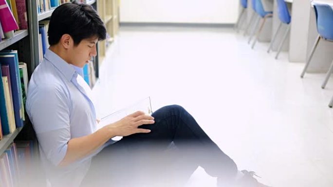 亚洲男大学生在图书馆阅读地板上进行学习研究。