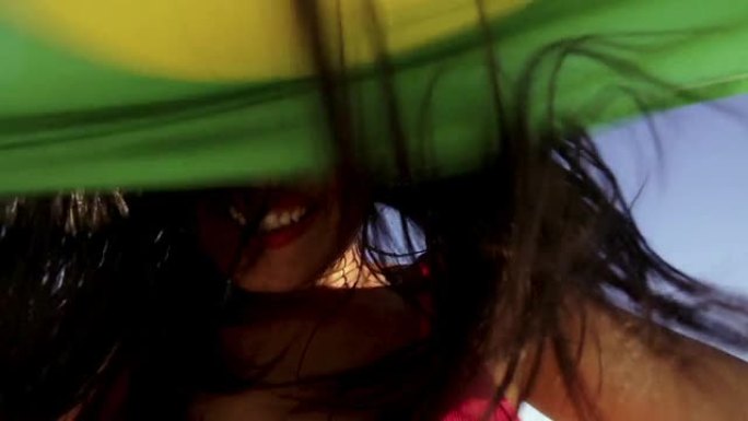 慢镜头中的巴西女孩在海滩上举着旗子