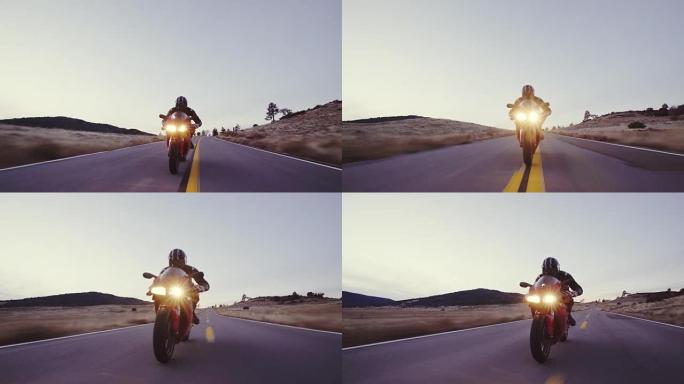 摩托车手骑着摩托车沿着直行的乡间小路在日落时高速行驶