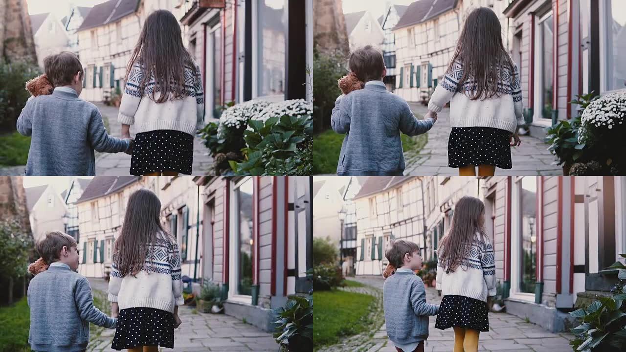 摄像机跟着两个小孩牵着手走路。慢动作后视图。女孩和男孩在老城区游荡。兄弟姐妹