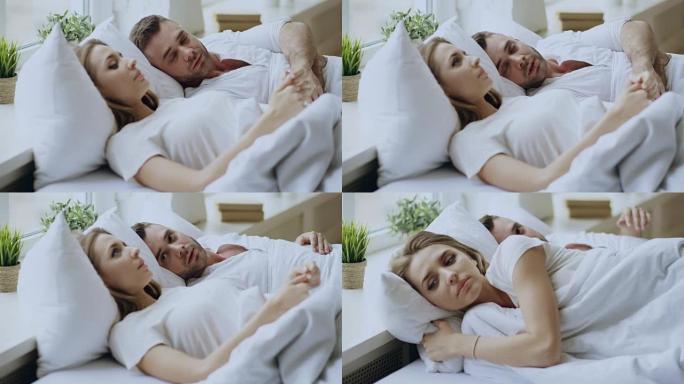 有感情问题的夫妇躺在家里的床上进行情感对话的特写镜头。年轻女子拒绝她的男朋友