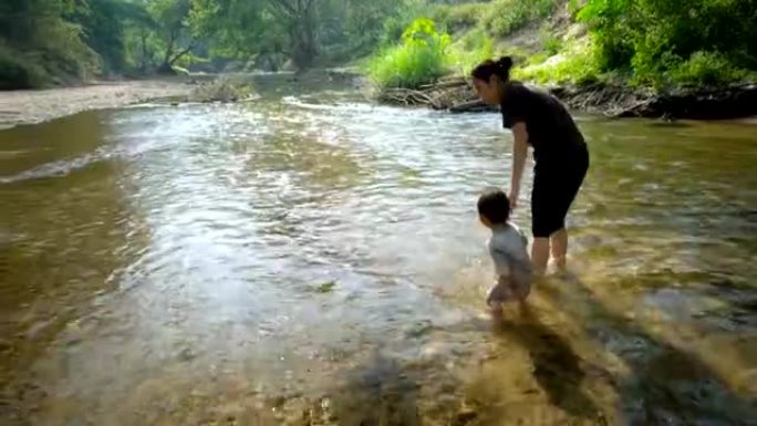 男婴和母亲一起在小溪玩耍。
