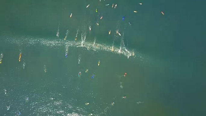 在阳光明媚的巴厘岛，初学者的空中人群划桨并捕捉小浪