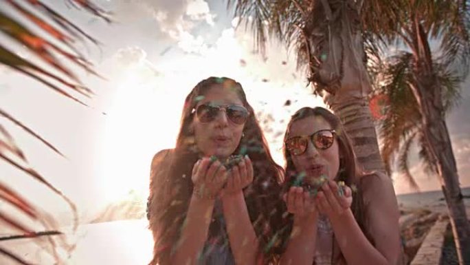 年轻女性在棕榈树海滩用五彩纸屑庆祝