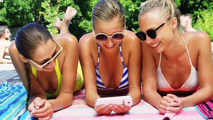 微笑的女性在游泳池边休息时使用手机