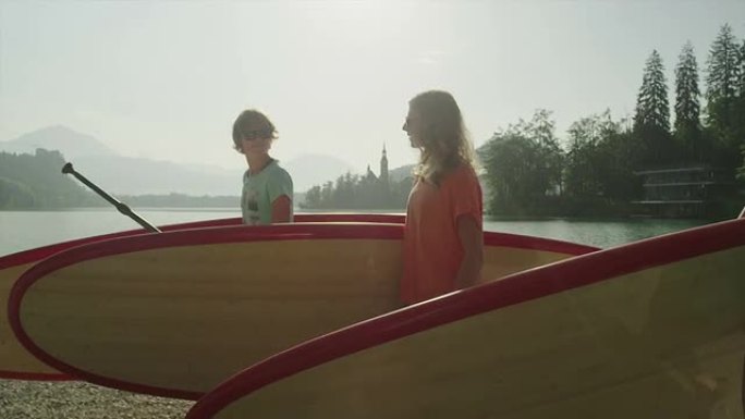 慢动作: 快乐的冲浪女孩背着SUP板到湖上