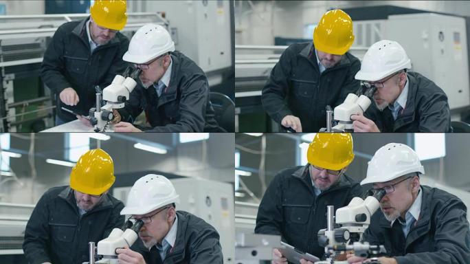 高级工程师正在工厂的显微镜下检查细节。第二名员工将数据放入平板电脑。