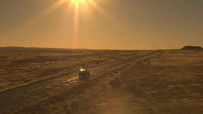 空中: 对面车道上的两辆汽车驶过阳光明媚的荒芜荒野