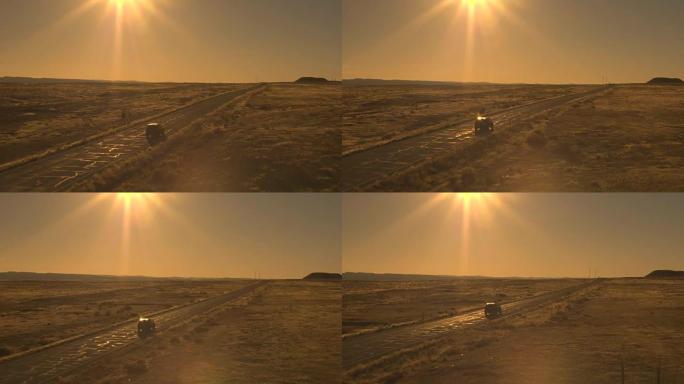 空中: 对面车道上的两辆汽车驶过阳光明媚的荒芜荒野