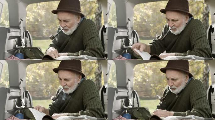 老人在车后抽烟斗和读书