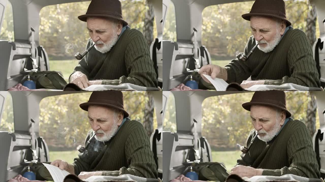 老人在车后抽烟斗和读书