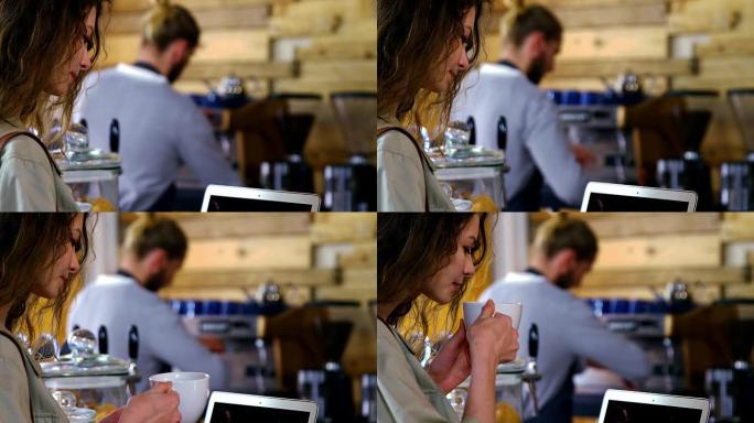 女人在喝咖啡时使用笔记本电脑