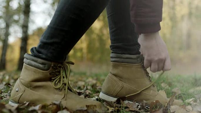 特写，女人在秋叶上系鞋带