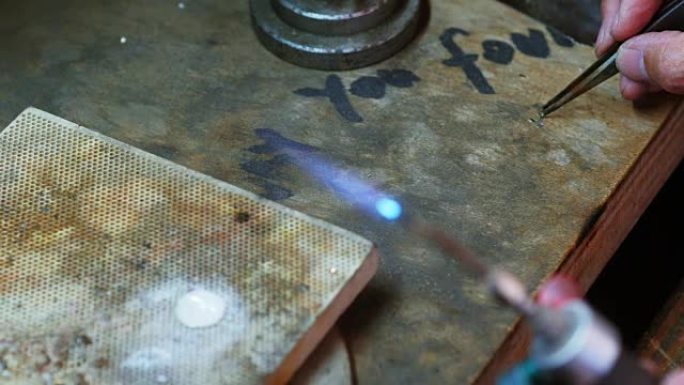 手工艺者吹着火炬融化金属的特写镜头