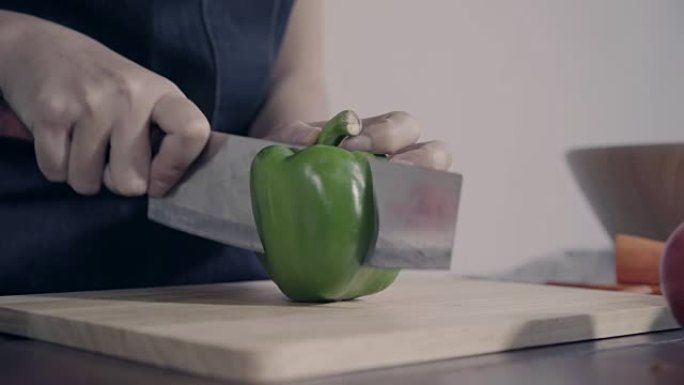 首席女士制作沙拉健康食品并在砧板上切碎甜椒的特写镜头。