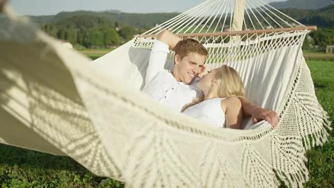 慢动作: 大自然中恋爱的女友和男友在吊床上聊天。