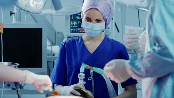 在医院手术室中，麻醉师对患者使用麻醉面罩，助手用碘消毒切口，外科医生等待开始手术。