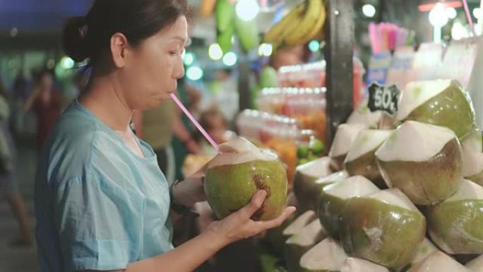 妇女在泰国街头食品上购买椰子