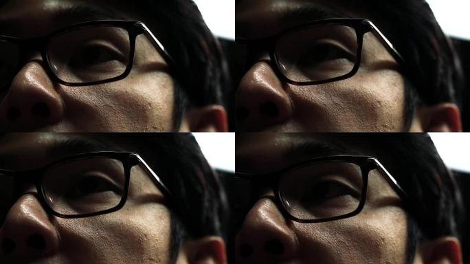 4k镜头的亚洲男子眼睛戴着眼镜在他的电脑屏幕上工作