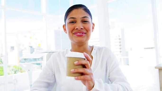 微笑的女人在办公室喝咖啡
