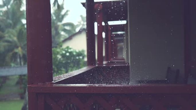 慢动作: 大雨落在俯瞰热带后院的木制门廊上。