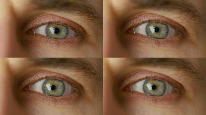眨眼男人眼睛的特写。它是灰色的，有棕色的点。以暖色拍摄。