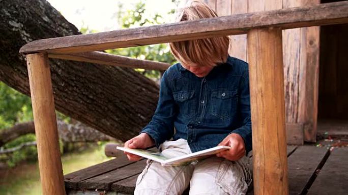 坐在树屋里读儿童读物的男孩