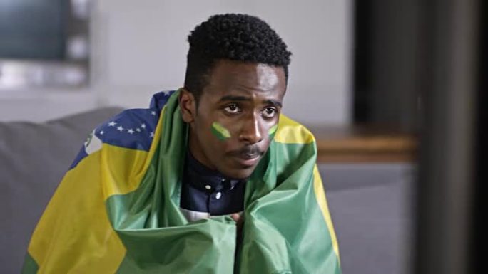 非洲男子支持巴西足球队并观看电视比赛